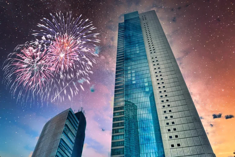 高層ビルのそばで夜空に花火が上がる都市夜景のイメージ
