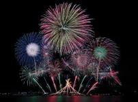 水辺の夜空に色とりどりの花火が広がるイメージ