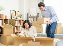 段ボール箱に荷物を詰めて引っ越しの準備をする夫婦