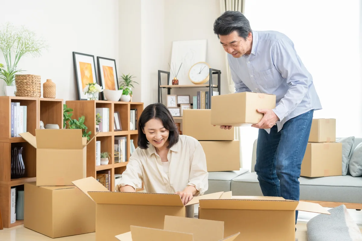 段ボール箱に荷物を詰めて引っ越しの準備をする夫婦