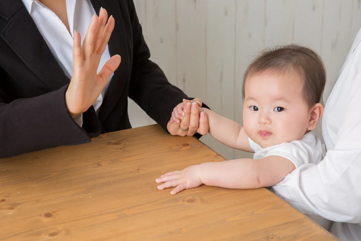乳児を抱いて区役所の窓口で入所申込を相談する母親