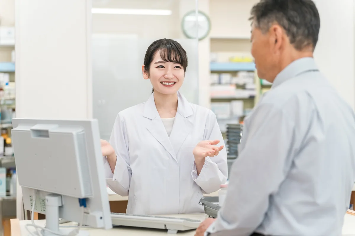 保険証を使って薬局で薬の説明を受ける人