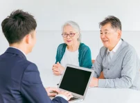 窓口で職員に手続きの相談をする高齢の夫婦