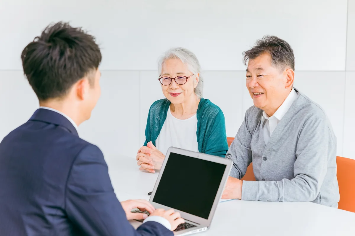 窓口で職員に手続きの相談をする高齢の夫婦