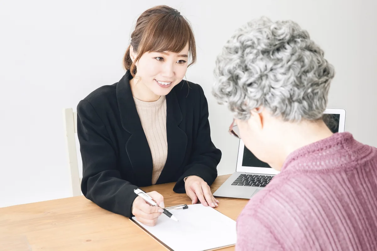 区役所の窓口で手続きについて相談する高齢女性
