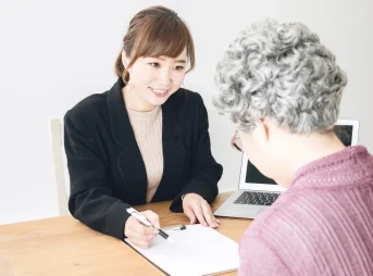 区役所の窓口で職員に手続きを相談する高齢の女性