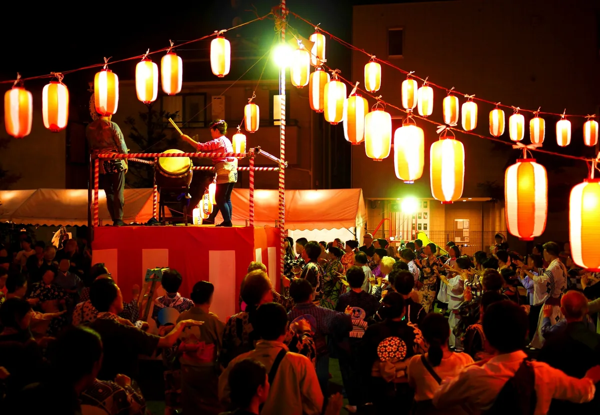 提灯の下で地域の祭りを楽しむ人々のイメージ