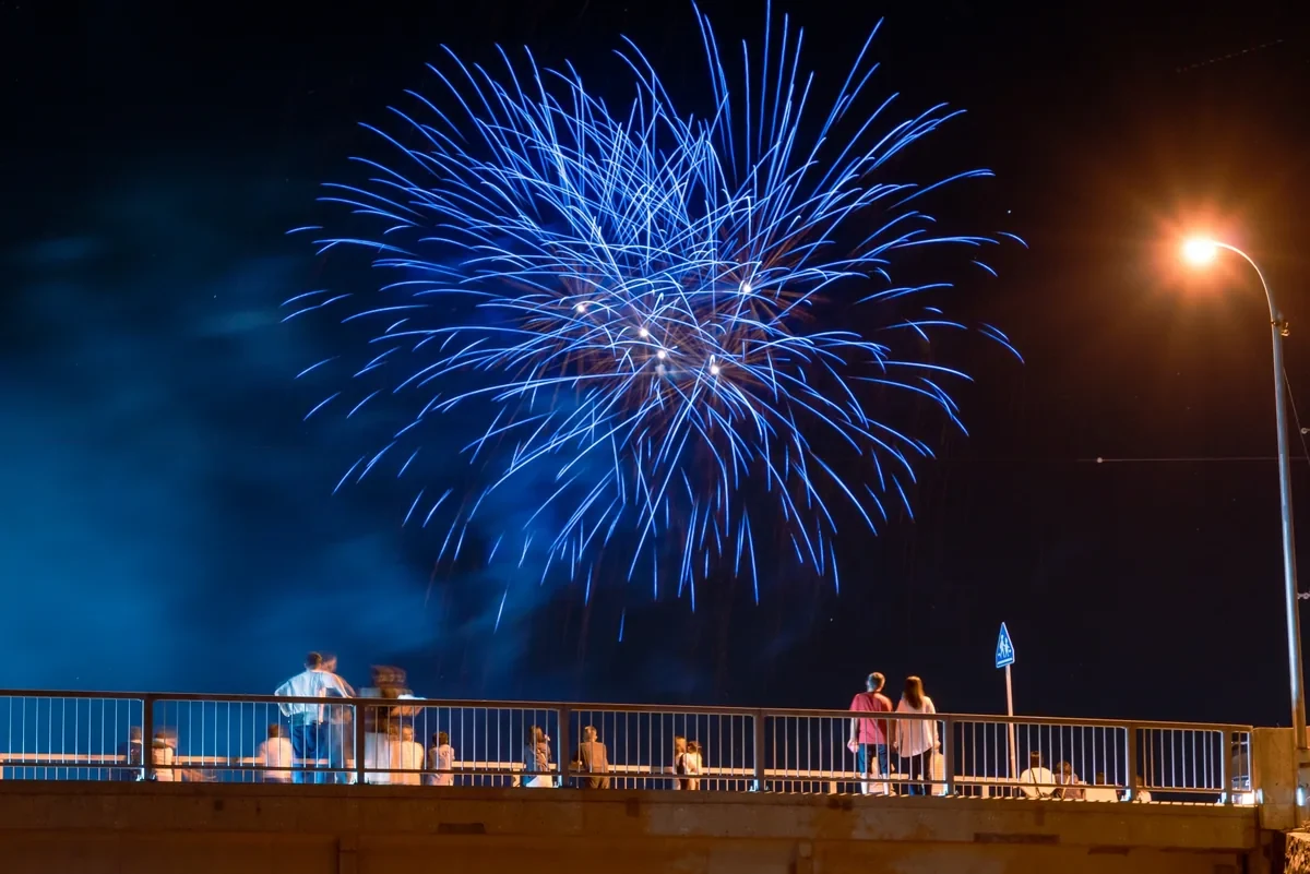 夜空の青い花火を眺める人々のイメージ